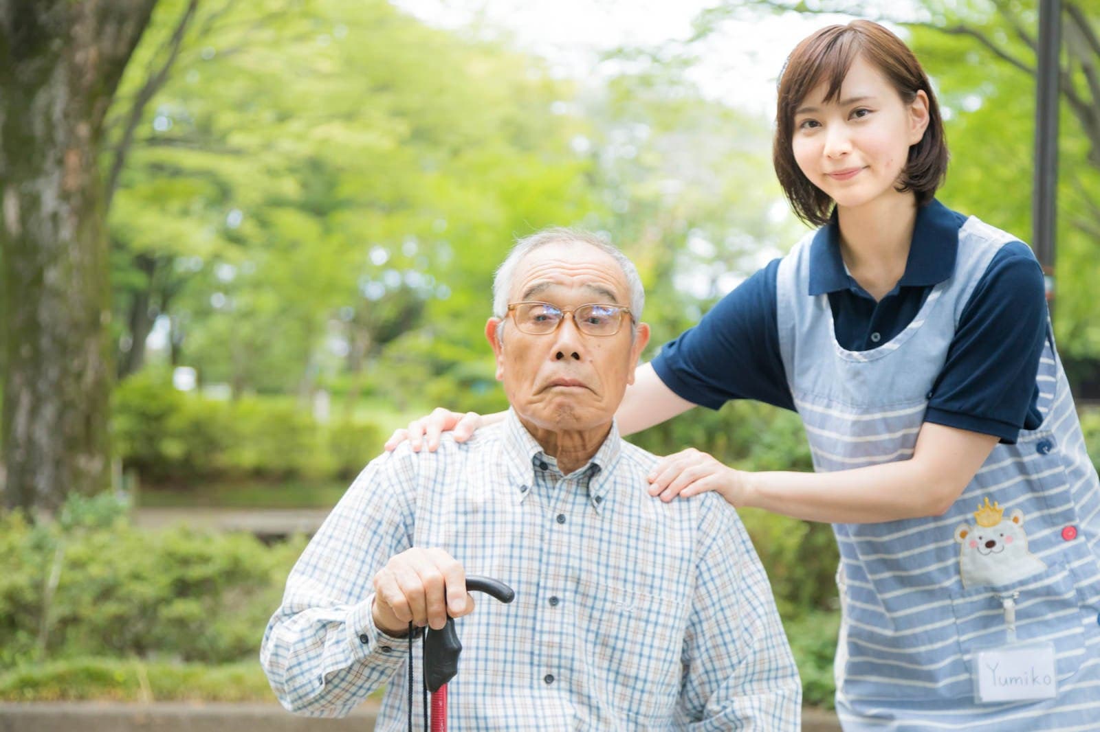 公園で高齢者の肩に優しく手を添える介護士の女性